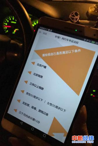 小李拿手机展示滴滴平台的网约车司机标准 中新经纬 吴一尘摄